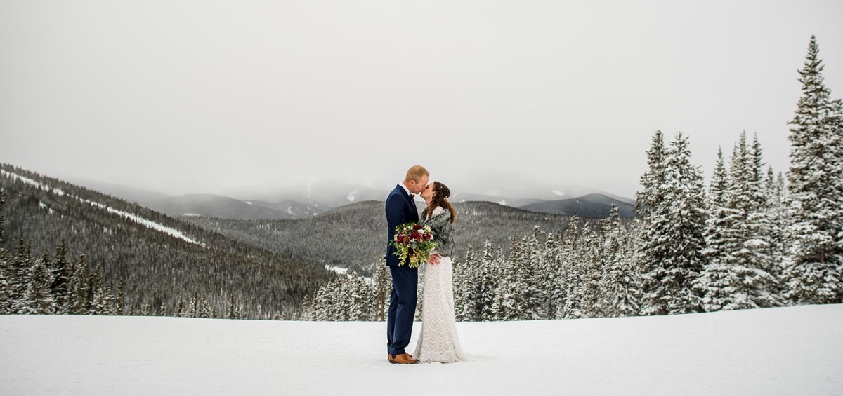 bride and groom kissing at top of mountain